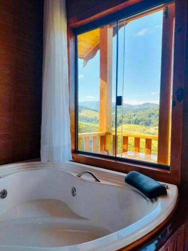 a bath tub in a room with a window at Chalé Caminho das Flores in Santo Antônio do Pinhal