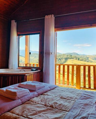 a bedroom with a bed and a large window at Chalé Caminho das Flores in Santo Antônio do Pinhal