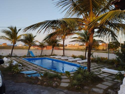 a swimming pool with lounge chairs and a palm tree at Linda casa Taiba in São Gonçalo do Amarante
