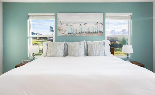 a bedroom with a large white bed with two windows at Perch - Sierra Retreat 34 in Coupeville