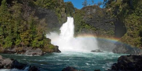 a rainbow in front of a waterfall on a river at cabaña vista hermosa neltume in Neltume