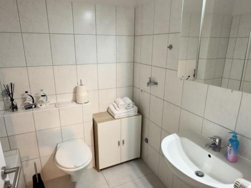 Un baño blanco con inodoro y lavabo. en FeWo Küstenglück - Wilhelmshaven, en Wilhelmshaven