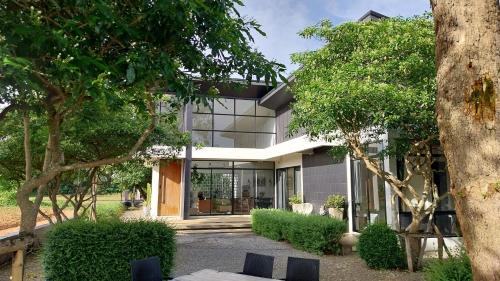 a house with glass windows and trees at THE OAK’S in Chiang Rai