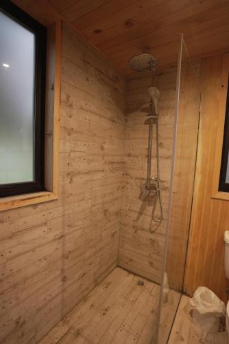 a shower in a wooden room with a window at Pucontours River Lodge in Pucón