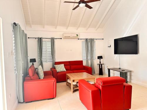 a living room with red furniture and a flat screen tv at Jamnick Vacation Rentals - Fern Court, Richmond Estate, St Ann, Jamaica in Ocho Rios
