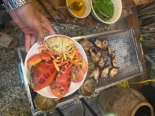 a person holding a plate of food with a crab at Về Nhà Homestay - đảo Phú Quý in Cu Lao Thu