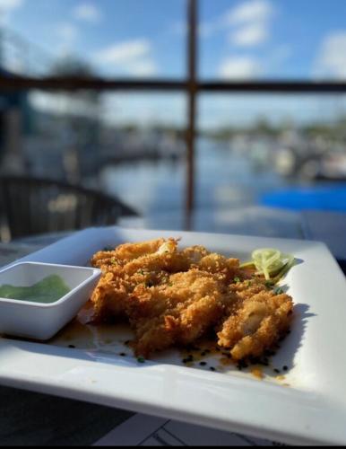a plate of food with a bowl of green dipping sauce at Paradise key largo in Key Largo