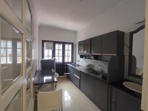 a kitchen with black cabinets and a table and a sink at Orient Glory Holidays in Edappally