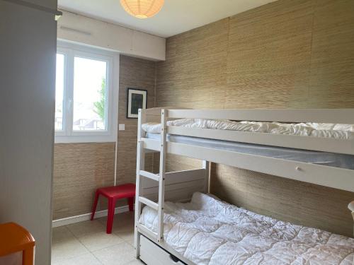 Ce lit se trouve dans un dortoir doté de 2 lits superposés et d'une chaise rouge. dans l'établissement Appartement Spacieux proche Plage avec Balcon et Parking - Villers-sur-Mer - FR-1-712-85, à Villers-sur-Mer