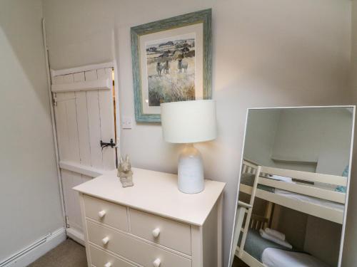 ein Schlafzimmer mit einer Lampe auf einer Kommode mit einem Spiegel in der Unterkunft Pheasant Cottage in Ilfracombe