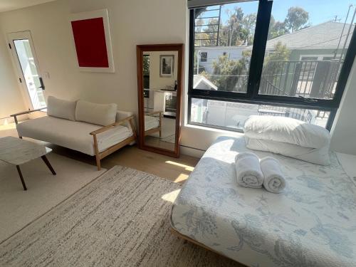 a bedroom with a bed and a chair and a window at Modern Bright New Studio with Roof-top Deck Walk to Santa Monica Beach, FreeWiFi, Parking in Santa Monica