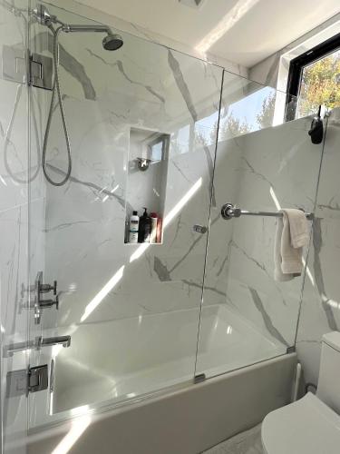 a white bathroom with a shower and a toilet at Modern Bright New Studio with Roof-top Deck Walk to Santa Monica Beach, FreeWiFi, Parking in Santa Monica