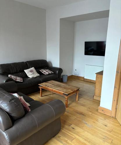 a living room with a leather couch and a coffee table at MacIver City Apartment Academy Street in Inverness