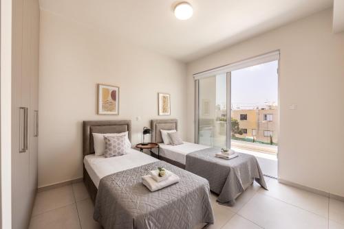 two beds in a room with a window at Protaras Mythical Seas in Protaras