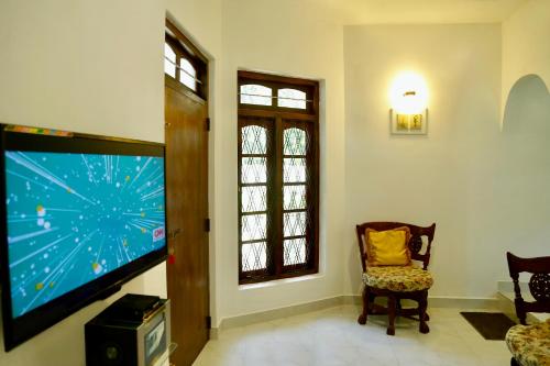 a living room with a flat screen tv and a chair at Gert's Aerovista villa in Seeduwa