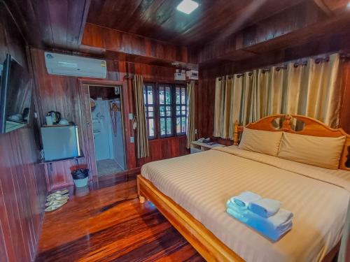 a bedroom with a bed with two towels and a television at Tayama Farm Khaoyai in Nakhon Ratchasima