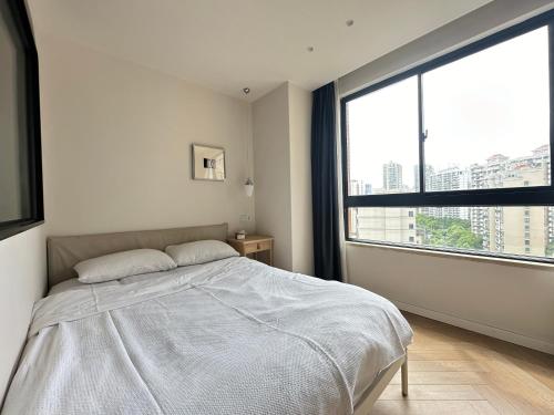 a bedroom with a bed and a large window at 同济佳苑公寓 in Shanghai