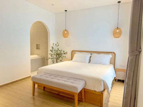 a bedroom with a large white bed with a bench at Mây House Grandworld Phu Quoc in Phu Quoc