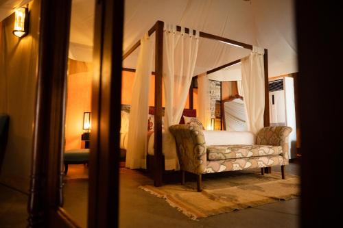 a bedroom with a canopy bed with a couch at Sangam Farms in Bhilwara