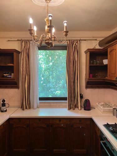 a kitchen with a window with a chandelier at Luxury 3 BR Vila in a forest 10min drive from city center in Budapest