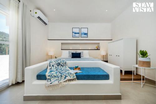 1 dormitorio blanco con 1 cama grande con sábanas azules en StayVista at Wellnest Natural Farms with private pool 4 hours from bangalore, en Chittoor