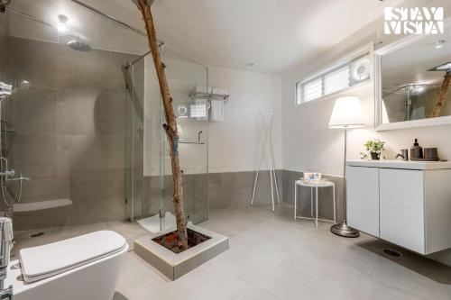 baño con aseo y ducha con árbol en StayVista at Wellnest Natural Farms with private pool 4 hours from bangalore, en Chittoor