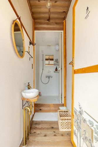 a bathroom with a sink and a mirror at Guesthouse & Kitchen Hace in Iwaki