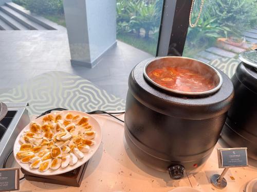 a table with a bowl of food and a pot of stew at The Cam Ranh Beach Front in Cam Ranh