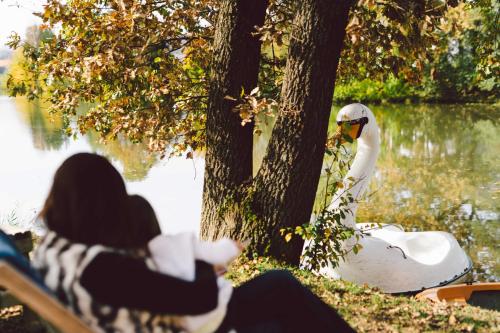 a woman sitting next to a white swan by a tree at Glamping Rajska vas in Šentjur