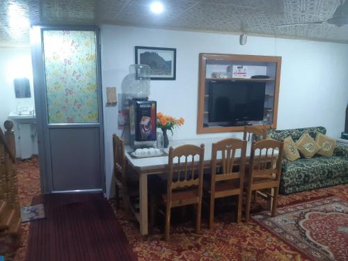 a living room with a table and chairs and a tv at Rose Bowl Guest House Homestay in Bāgh Chandpura