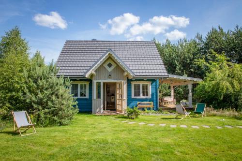 a blue house with chairs in the yard at Niebieski Domek nad Marychą in Stanowisko