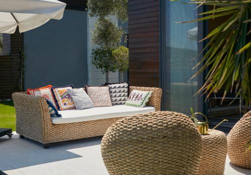 a rattan couch with pillows on a patio at Root Redrock Yalıkavak in Yalıkavak