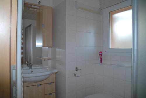 a white bathroom with a sink and a toilet at Appartment Aux Lilas in Les Geneveys-sur-Coffrane