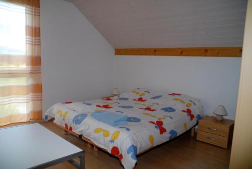 1 dormitorio con cama con edredón y ventana en Appartment Aux Lilas, en Les Geneveys-sur-Coffrane