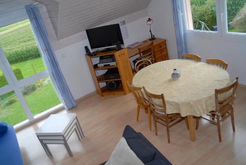 a room with a table and a tv and a table and chairs at Appartment Aux Lilas in Les Geneveys-sur-Coffrane