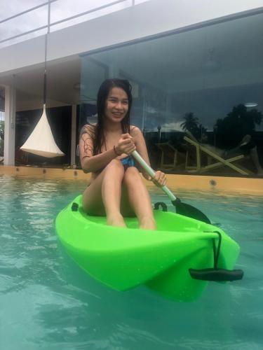 a woman sitting on a green boat in a pool at Daiya Pool Villa, Khaoyai in Ban Sathani Phut Rai