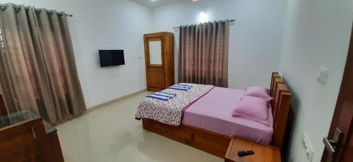 a bedroom with a bed with pink sheets and purple pillows at Dhara Dhvani Getaway Homes in Tindummal