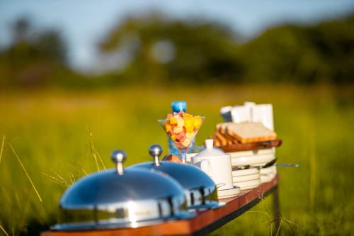 a picnic table with a tea pot and books at Escarpment Serengeti Luxury Camp in Serengeti