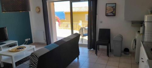 un salon avec un canapé, une table et une télévision dans l'établissement Appartement vue mer Aiguebelle, au Lavandou