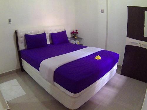 a bedroom with a bed with purple sheets and pillows at 24/7 Bed & Breakfast in Jimbaran