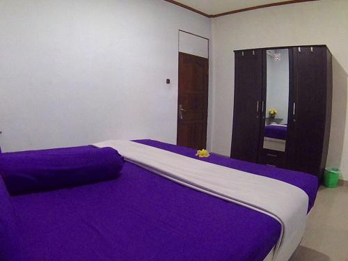 a bedroom with a purple bed with a mirror at 24/7 Bed & Breakfast in Jimbaran