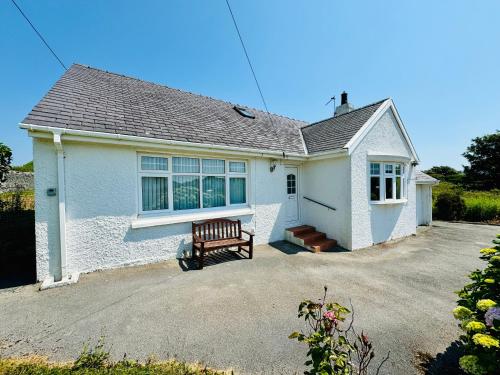 a white house with a bench in the driveway at TIRNANT- 3 Bed - GROUND FLOOR ROOMS -DOG FRIENDLY in Trearddur
