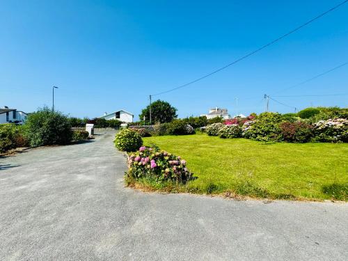 a parking lot with flowers in the grass at TIRNANT- 3 Bed - GROUND FLOOR ROOMS -DOG FRIENDLY in Trearddur