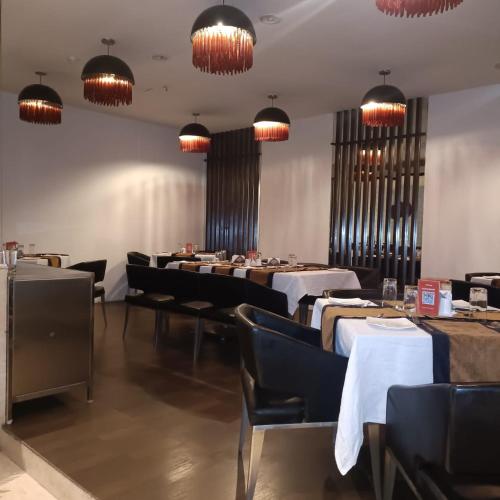 a dining room with tables and chairs and chandeliers at Royal Park Kakinada in Kākināda