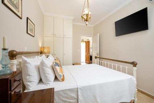 a bedroom with a white bed and a television at Venti Di Paxos in Lákka