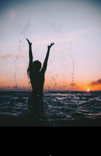 a woman standing in the ocean with her arms in the air at Cofanomare in Custonaci