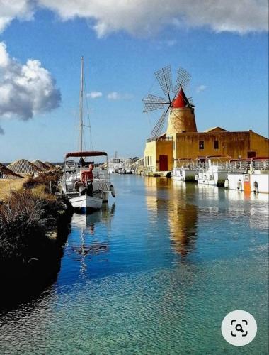 a boat in the water next to a windmill at Cofanomare in Custonaci