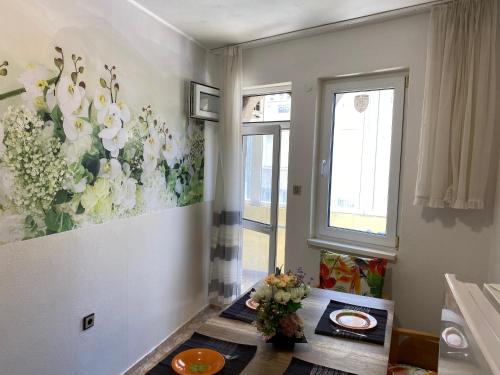 a room with a table and flowers on the wall at Centrum in Burgas City