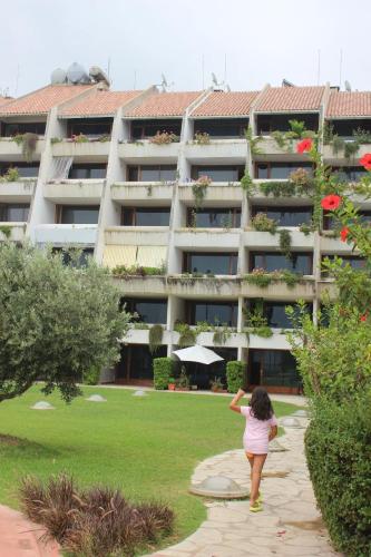 a woman standing in front of a large apartment building at Cimer SafraMarine Beach Resort in Safra