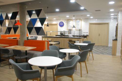 a cafeteria with tables and chairs and a kitchen at Holiday Inn Express San Sebastian de los Reyes by IHG in San Sebastián de los Reyes